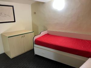 ein kleines Zimmer mit einem roten Bett und einem Schrank in der Unterkunft Bucco house in Nettuno