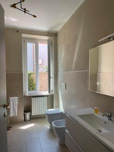 baño con aseo y lavabo y ventana en B&B Licia Home, en Voghera