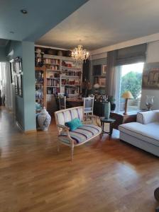 ein Wohnzimmer mit einem Sofa, Stühlen und einem Tisch in der Unterkunft Seaside Artistic Apartment in Glyfada in Athen