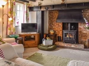a living room with a fireplace and a television at The Old Thatch in Hailsham