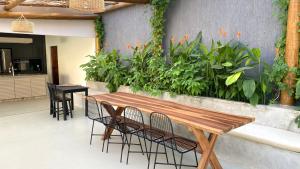 um pátio com uma mesa de madeira, cadeiras e plantas em Villa Parazinho em Paracuru
