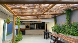 a patio with a wooden pergola and a kitchen at Villa Parazinho in Paracuru