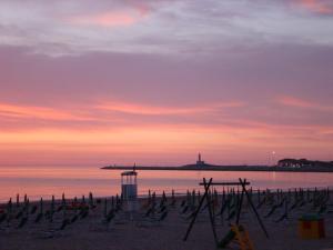 a beach with chairs and the ocean at sunset at Hotel Vela Velo Club Vieste in Vieste