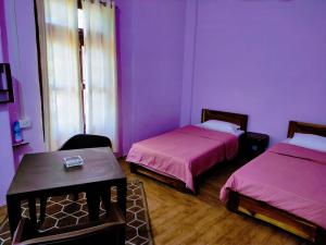 Habitación púrpura con 2 camas y mesa en Chawngthu Lodge en Āīzawl