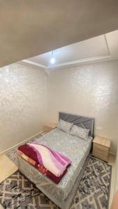 een kleine slaapkamer met een bed in de hoek bij Superbe appartement neuf in Agadir