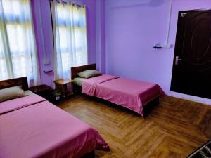 2 Betten in einem Zimmer mit lila Wänden und Holzböden in der Unterkunft Chawngthu Lodge in Aizawl
