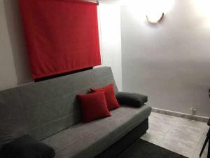 マドリードにあるAgradable apartamento en zona Malasaña Madridの赤い枕2つ付きのソファが備わる客室です。