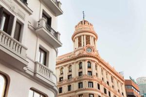 un edificio con una torre dell'orologio sopra di A Unos Pasos a Gran Via Madrid Xl a Madrid