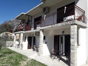 a white house with a balcony and tables and chairs at Apartments Samardzic in Kotor