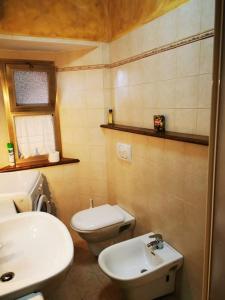 La salle de bains est pourvue de toilettes blanches et d'un lavabo. dans l'établissement Casa immersa nella natura, à Capanne di Sillano