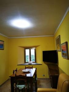 ein Wohnzimmer mit einem Tisch und einem TV in der Unterkunft Casa immersa nella natura in Capanne di Sillano