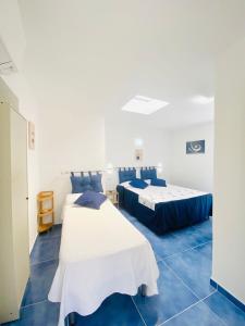 two beds in a room with blue tiles at Casa Leo in Anacapri