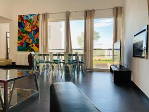 ein Wohnzimmer mit einem Tisch, Stühlen und einem Gemälde in der Unterkunft Contempory exclusive Sitges area in Barcelona