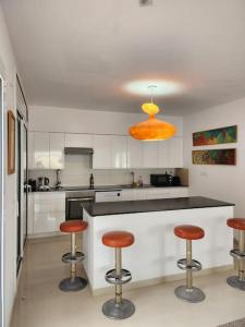 eine Küche mit drei Barhockern und gelbem Licht in der Unterkunft Contempory exclusive Sitges area in Barcelona