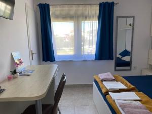 a room with a table and a window with blue curtains at Guesthouse Šimag in Rab