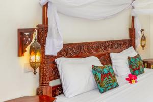 a bed with a wooden headboard and white pillows at TASNEEM Aparthotel in Jambiani