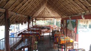 ein Restaurant mit Tischen und Stühlen und einem Strohdach in der Unterkunft Hotel LOL-HA in Cobá