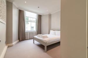 a white bedroom with a bed and a window at Canal Crescent Charm Flat with Stunning Views Little Venice in London