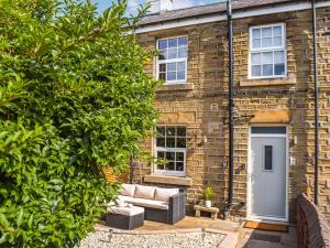 a brick house with a couch in front of it at Yorkshire Cottage in Clayton West