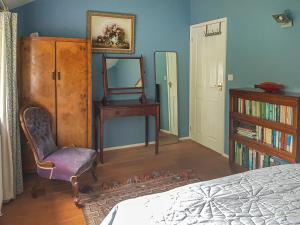 ein Schlafzimmer mit einem Bett, einem Stuhl und einem Spiegel in der Unterkunft Coach House in Ashford