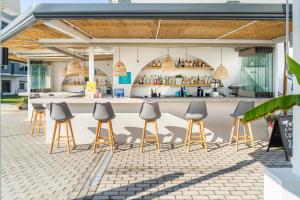 an outdoor kitchen with stools and a bar at Akritas Hotel Pefkochori in Pefkohori
