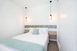 ein kleines Schlafzimmer mit einem weißen Bett und zwei Leuchten in der Unterkunft Meraki3-Picina cubierta climatizada in Chiclana de la Frontera + 26 Fotos