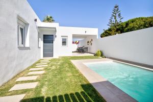 biały dom z basenem i trawą w obiekcie Casa Piscina Cubierta Climatizada 3 w mieście Chiclana de la Frontera