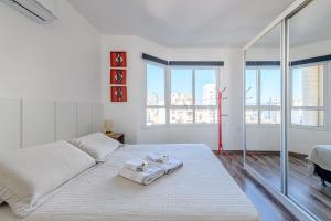 a white bedroom with a large bed with towels on it at Loft Centro Histórico, Completo e Confortável 502 in Porto Alegre