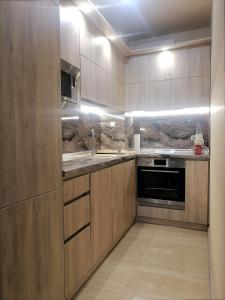 cocina con armarios de madera, fregadero y fogones en Апартамент Релакс, en Golden Sands