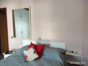 um quarto com uma cama com almofadas vermelhas e um espelho em Quarto, piscina, ar condicionado em Encantado