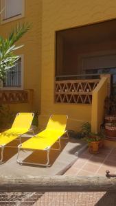 dos sillas amarillas sentadas en un patio junto a un edificio en Los olivos apartamento, en Vera
