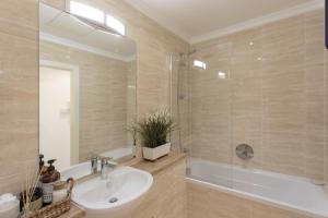 a bathroom with a sink and a shower and a tub at Light Airy Double Short walk from Elizabeth Line in Goodmayes