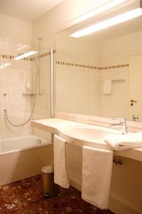 a bathroom with a sink and a shower and a tub at Hotel Panorama Hamburg-Harburg in Hamburg