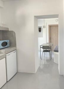 cocina blanca con mesa y microondas en 31 Seafront Apartment, en Kampos