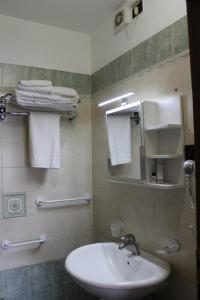ein Badezimmer mit einem Waschbecken, einem Spiegel und Handtüchern in der Unterkunft Residence La Noce con Angolo Cottura in Chivasso
