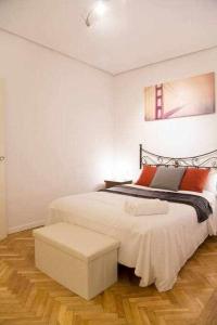 マドリードにあるUn Elegante Piso Para Descubrir Madridの白いベッドルーム(ベッド1台、スツール付)