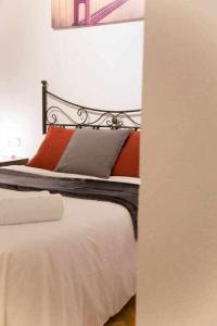 a bed with orange and grey pillows in a room at Un Elegante Piso Para Descubrir Madrid in Madrid