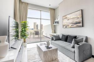 uma sala de estar com um sofá cinzento e uma grande janela em Downtown Ultra Luxury 1BR - 15 Northside - Burj Khalifa View no Dubai