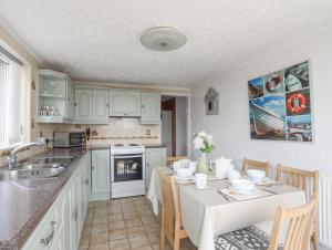 a kitchen with green cabinets and a table with chairs at Morlais Voice of the Sea in Aberffraw