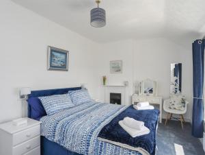 a bedroom with a blue bed with towels on it at Morlais Voice of the Sea in Aberffraw