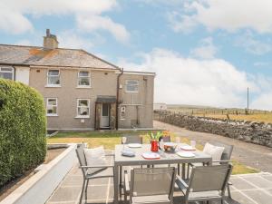 a table and chairs on a patio in front of a house at Morlais Voice of the Sea in Aberffraw
