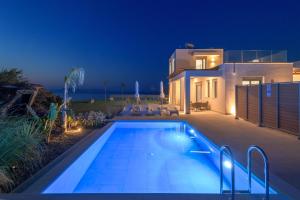 a swimming pool in front of a house at night at Panaxia Villas in Theologos