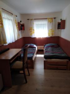 a room with two beds and a desk and a table at Chata pod Lysou Horou in Ostravice
