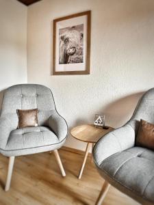 een woonkamer met 2 stoelen en een foto van een leeuw bij Gasthof Auwirt in Sankt Michael im Lungau