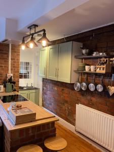 a kitchen with green cabinets and a brick wall at Rock Studio -Near City Centre-Free on street Parking-Free Wi-Fi in Leeds