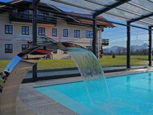 una fuente de agua en una piscina con un edificio en el fondo en Alluring Holiday Home in Ubersee with Whirlpool, en Übersee