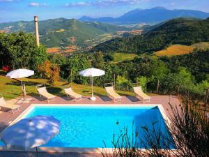 a swimming pool with chairs and umbrellas on a mountain at Luxurious Villa in Acqualagna with Swimming Pool in Acqualagna
