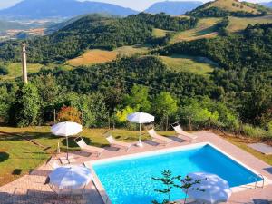 a swimming pool with umbrellas and chairs with a mountain at Luxurious Villa in Acqualagna with Swimming Pool in Acqualagna