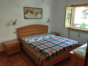 una camera da letto con un letto con una coperta scozzese sopra di Mimosa a Tagliacozzo