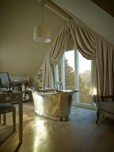 Cette chambre dispose d'une grande baignoire et d'une fenêtre. dans l'établissement Dormy House Hotel, à Broadway